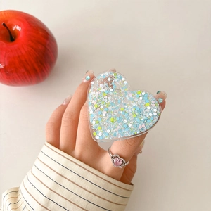 Close-up of heart-shaped phone grip with blue glitter sequins on a striped background