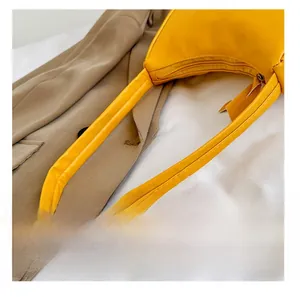 Detail shot of the bright yellow glossy leather handle and metal zipper of the underarm bag