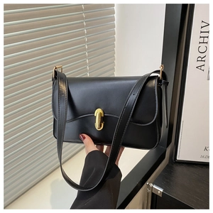 Close-up of black leather underarm bag featuring a vintage gold oval metal clasp detail