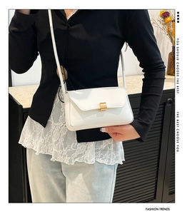 Close-up of white leather baguette bag featuring a stylish gold square metal clasp