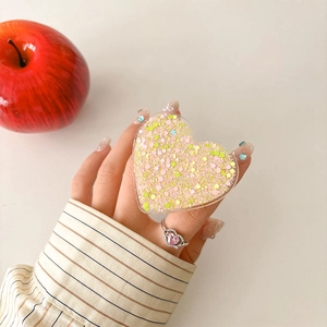 Detail of heart-shaped glitter phone socket with pink sequins being held by hand
