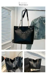 Detail of black tote bag with crocodile pattern, chain strap, and magnetic closure