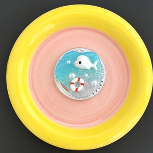 Detail of 3D resin whale and pearl pop socket with blue ripple texture on a pink dish