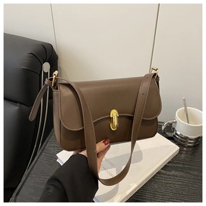 Detail of a brown leather shoulder bag with a gold rectangular metal swivel lock