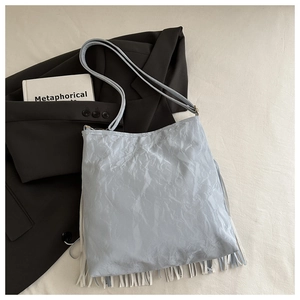 Dettaglio borsa a secchiello azzurra con trama stropicciata e lunghe frange decorative