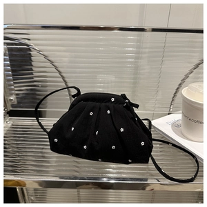 Détail d'un sac nuage plissé noir avec motifs floraux blancs posé sur une étagère