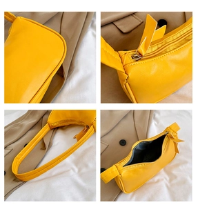 Detail view of bright yellow PU leather underarm bag with silver zipper and shoulder strap