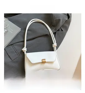 Detail of white baguette shoulder bag featuring gold square buckle and knotted strap