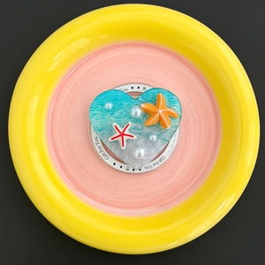 Detail of heart-shaped ocean phone grip with resin starfish and pearls on a ceramic dish