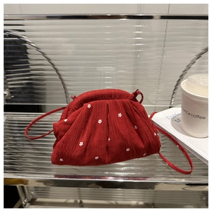 Détail du sac rouge à fleurs brodées avec texture plissée dans un décor chic