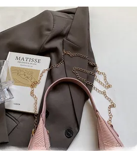 Detail of pink woven texture handbag with golden chain strap on a dark blazer