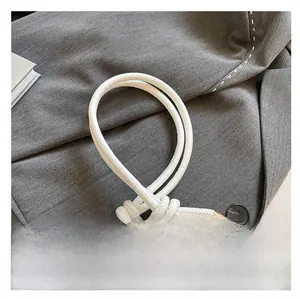 Detail of white leather shoulder strap with unique knot design and gold metal hardware