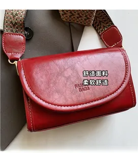 Macro shot of red leather small square bag with colorful woven strap and golden buckle