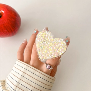 Detail of heart-shaped glitter phone grip with yellow sequins and pink diamond ring accessory