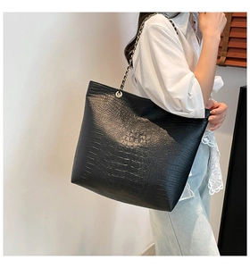 Close-up of black crocodile texture tote bag with elegant gold chain strap detail