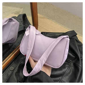 Detail of light purple faux leather shoulder bag with zipper and wide strap held by hand