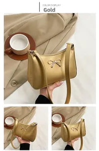 Detailed close-up of golden metallic bow decoration and shiny finish on the shoulder bag