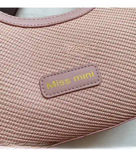 Detailed macro view of light pink woven fabric texture and Miss Mini embroidered patch