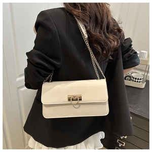 Détail du sac bandoulière crème avec fermoir carré doré et bandoulière en chaîne chic