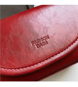 Macro detail of red leather bag showing white contrast stitching and embossed logo