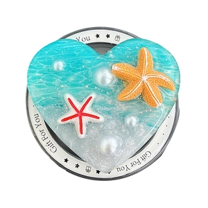 Ocean-themed heart phone grip with waves, stars and pearls on a white gift box