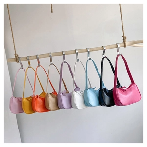 Detailed view of nine candy-colored minimalist underarm bags hanging on a rustic wooden branch