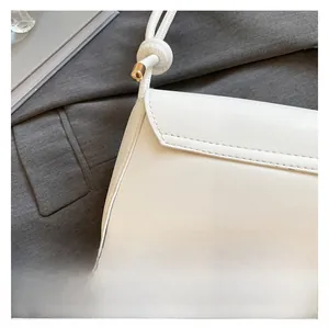 Close-up of premium white leather texture and uniform stitching on minimalist flap bag