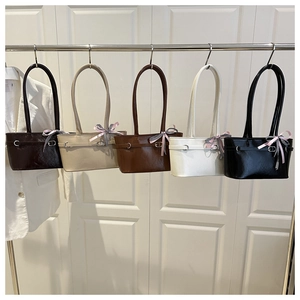 Detail view of colorful PU leather baguette bags with decorative pink ribbon and metal buckles