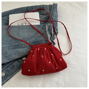 Gros plan d'un sac à bandoulière rouge plissé à motif floral posé sur du denim