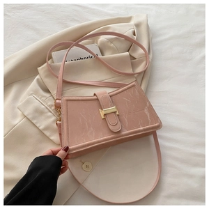 Detail of pink baguette bag with marble texture and golden buckle on beige blazer