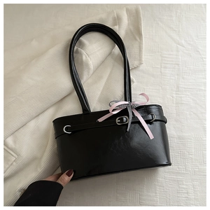 Gros plan du sac cabas noir avec lanières décoratives et un nœud en ruban rose élégant