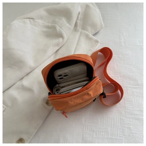 Detailaufnahme der orangefarbenen Nylon-Umhängetasche mit Platz für Handy und Geldbörse