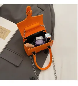 Interior view of mini orange box bag showing capacity for cosmetics and lipsticks