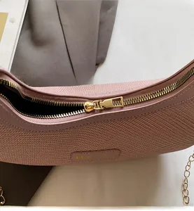 Close-up of pink textured handbag with gold zipper detail and fine chain strap