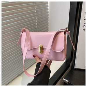 Detail of pink leather handbag featuring a curved flap and golden oval twist lock