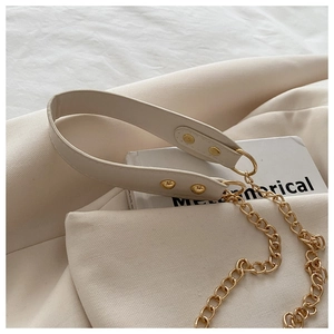 Dettaglio tracolla in pelle crema con catena dorata e rivetti metallici su borsa chic