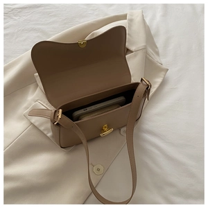 Close-up of brown leather underarm bag with gold metal buckle and spacious interior