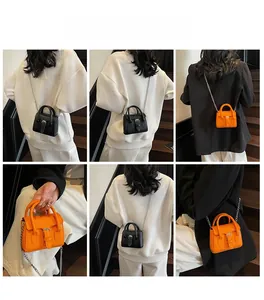 Mini crossbody bags in black and orange leather with silver chains on a model