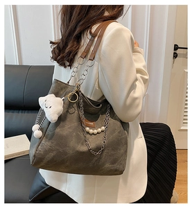 Detail view of grey canvas tote bag featuring metal chain strap and pearl cloud charm