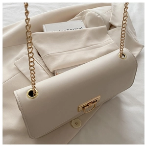 Dettaglio della borsa a busta in pelle beige con catena dorata e chiusura metallica