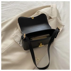 Detail of black leather flap shoulder bag showing spacious interior with phone and wallet