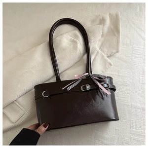 Détail du sac à bandoulière en cuir ciré marron foncé avec un nœud décoratif