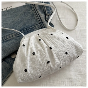 Détail du sac bandoulière plissé blanc avec broderie florale noire et fine bandoulière
