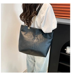 Model wearing a large black crocodile pattern tote bag with golden metal chain strap