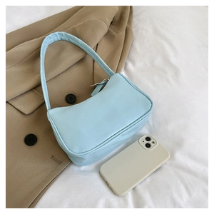 Light blue baguette bag on white fabric next to a khaki jacket and a phone for size