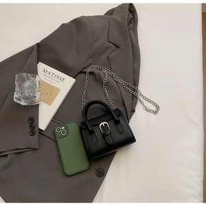 Gros plan d'un mini sac carré noir avec chaîne argentée sur tissu de blazer gris