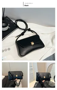 Detail of black matte leather shoulder bag with gold metal buckle and knotted strap