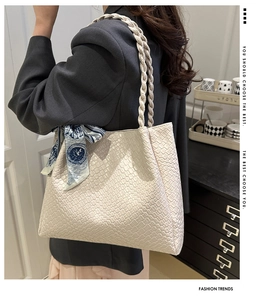 Detail of cream woven tote bag with silk scarf handle on model in modern setting