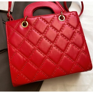 Detailed close-up of bright red patent leather handbag with quilted diamond pattern