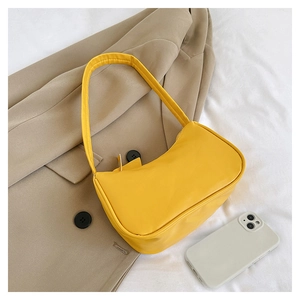 Detailed view of a mini yellow underarm bag in smooth PU leather with phone for size reference